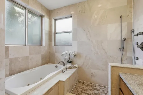 a bathroom with a granite countertop tub sink and mirror