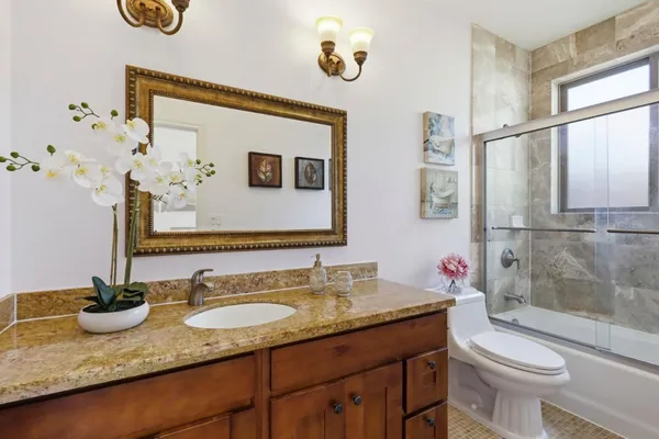 a bathroom with a granite countertop sink and a mirror