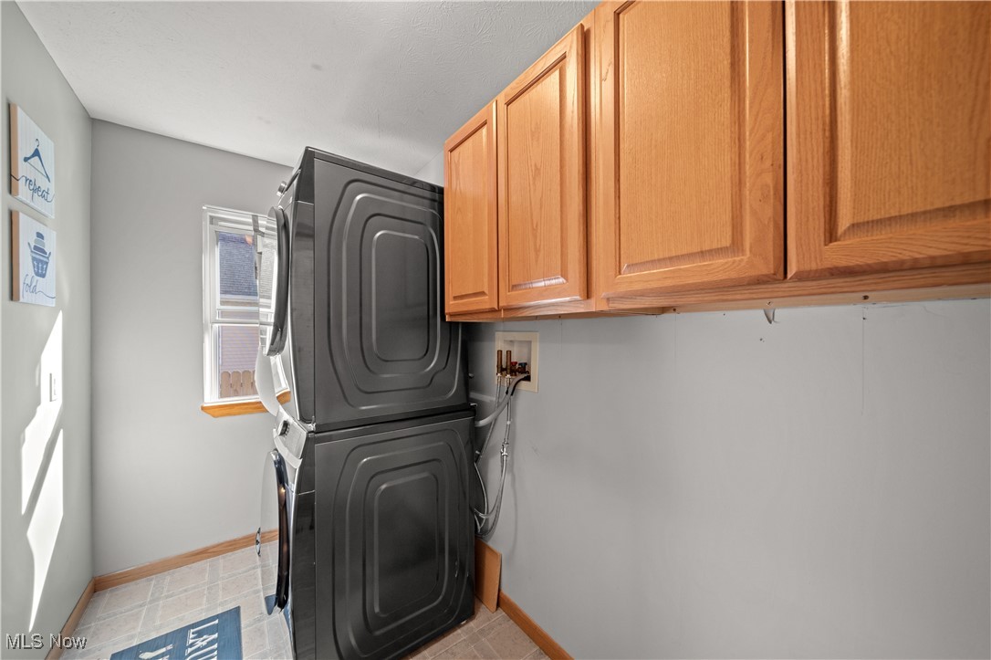 1951 Haines Road Madison, OH 44057 - Photo 15 of 44 Clothes washing area featuring cabinets and stacked washing maching and dryer
