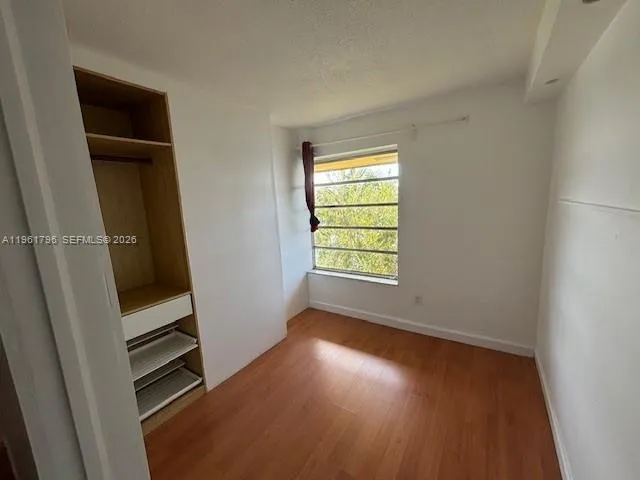 an empty room with wooden floor cabinet and windows