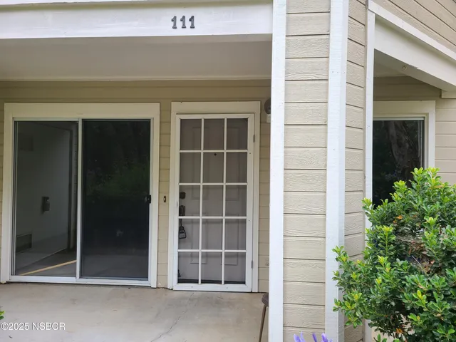 a view of a white house with a swimming pool and a large tree