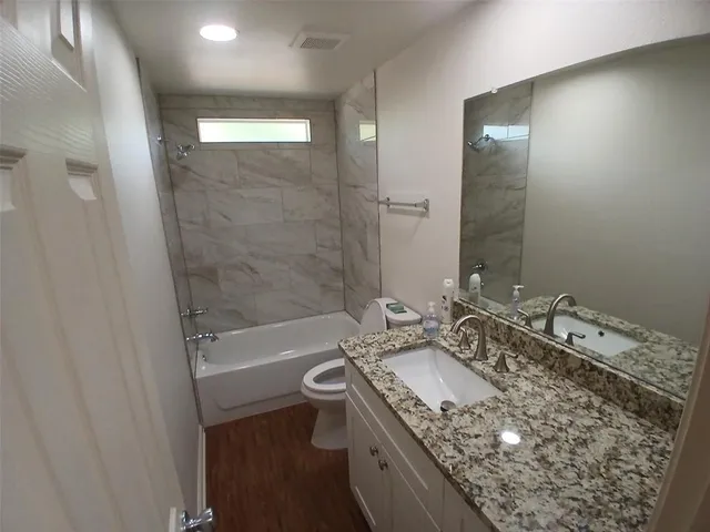 a bathroom with a granite countertop sink a mirror and a bathtub