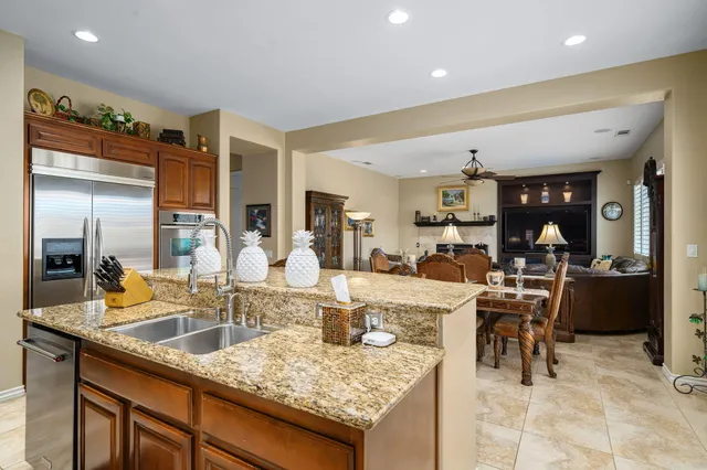 a kitchen with kitchen island granite countertop a sink cabinets and stainless steel appliances