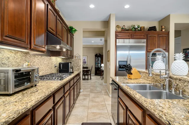 a kitchen with kitchen island granite countertop wooden cabinets and stainless steel appliances