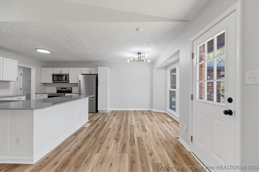 7847 Amesbury Road Fayetteville, NC 28311 - Photo 12 of 42 a large white kitchen with granite countertop a stove top oven a sink dishwasher and a refrigerator with wooden floor