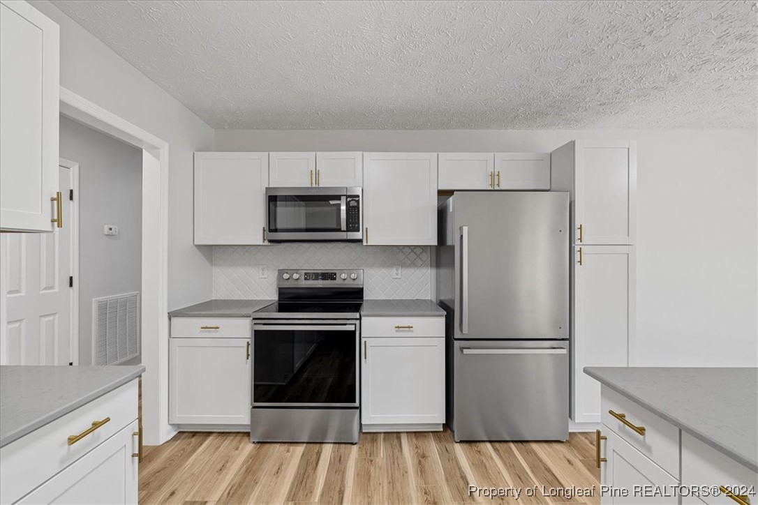 7847 Amesbury Road Fayetteville, NC 28311 - Photo 13 of 42 a kitchen with a refrigerator stove and white cabinets