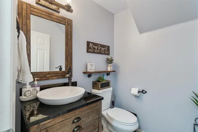 a bathroom with a granite countertop toilet sink and mirror