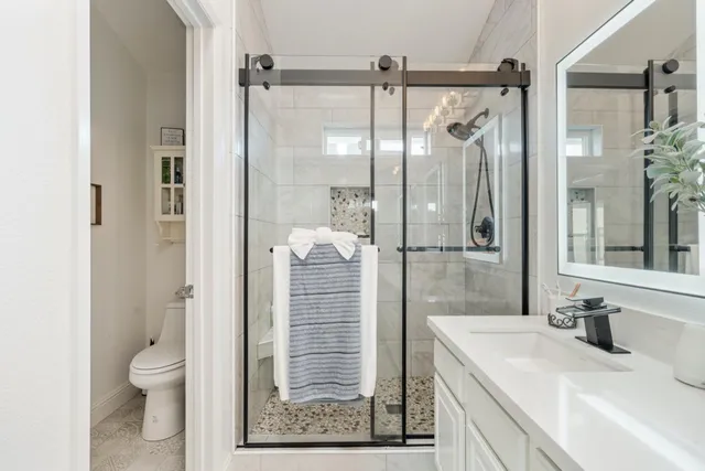 a bathroom with a granite countertop shower sink vanity and toilet