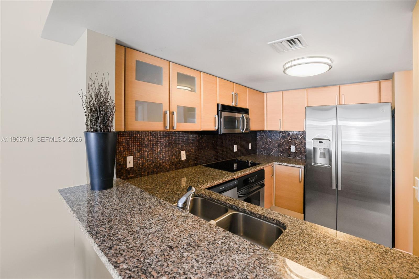 2101 Brickell Avenue, Unit 1704 Miami, FL 33129 - Photo 6 of 19 a kitchen with stainless steel appliances granite countertop a refrigerator a stove and a sink with wooden floor