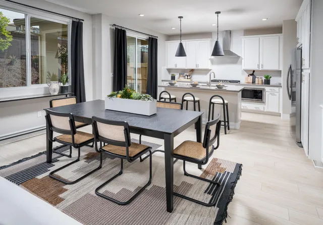 a kitchen with stainless steel appliances kitchen island granite countertop a stove a sink a dining table and chairs