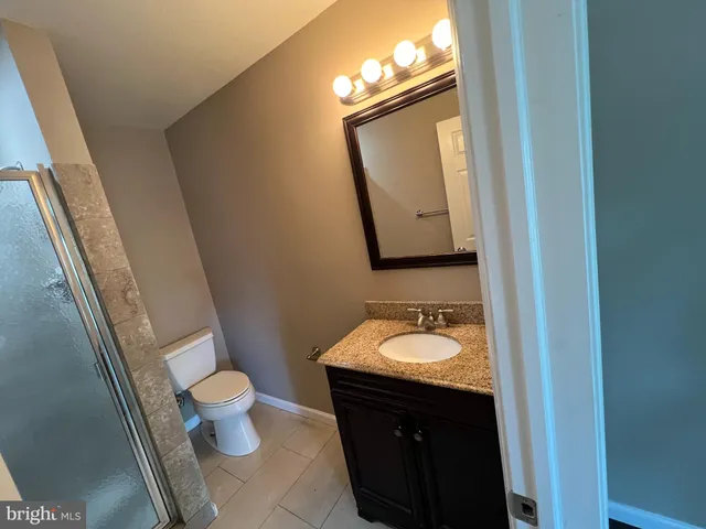 a bathroom with a granite countertop toilet sink and mirror