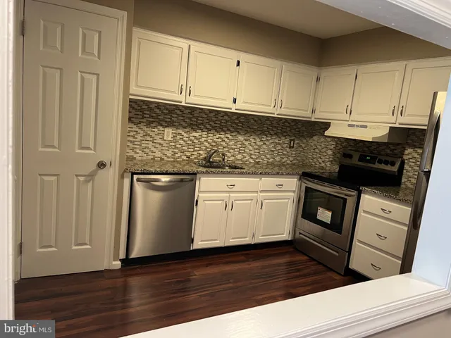 a kitchen with granite countertop white cabinets and black appliances