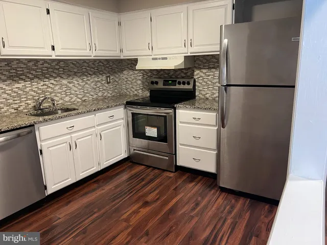 a kitchen with appliances cabinets and wooden floor