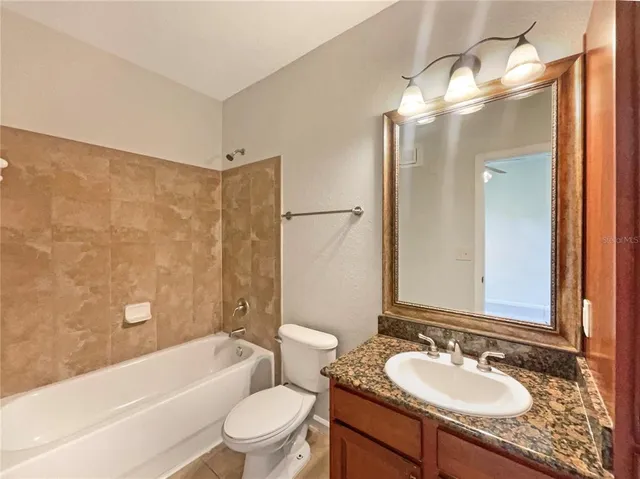 a bathroom with a granite countertop sink toilet mirror and shower