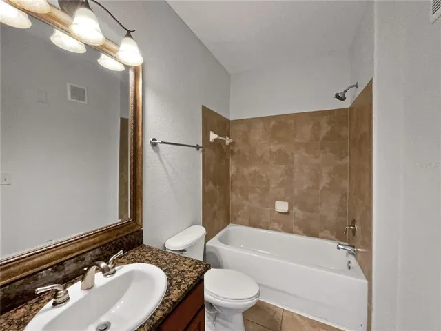 a bathroom with a bathtub shower sink vanity mirror and toilet