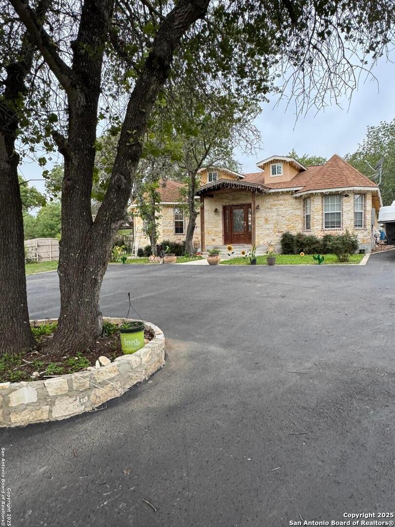 22739 Lazy Stream Drive Elmendorf, TX 78112 - Photo 15 of 20 a front view of a house with a garden and trees