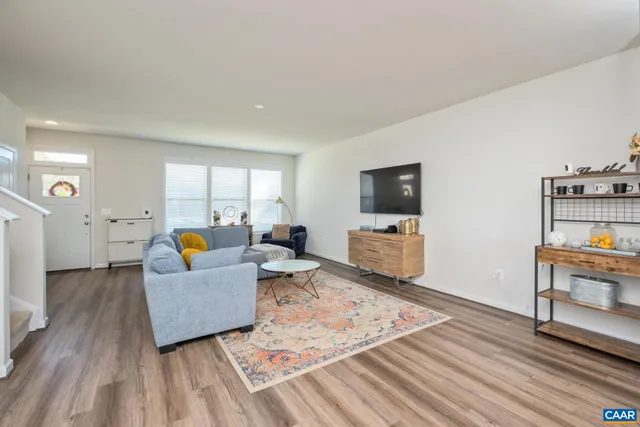 a living room with couch and a dining table with wooden floor