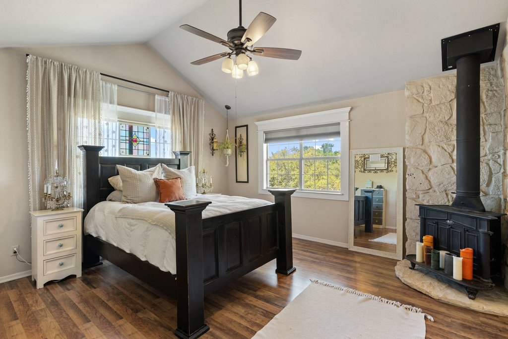 290 Sunset Ridge Dripping Springs, TX 78620 - Photo 13 of 39 Bedroom with dark wood finished floors, a wood stove, and multiple windows