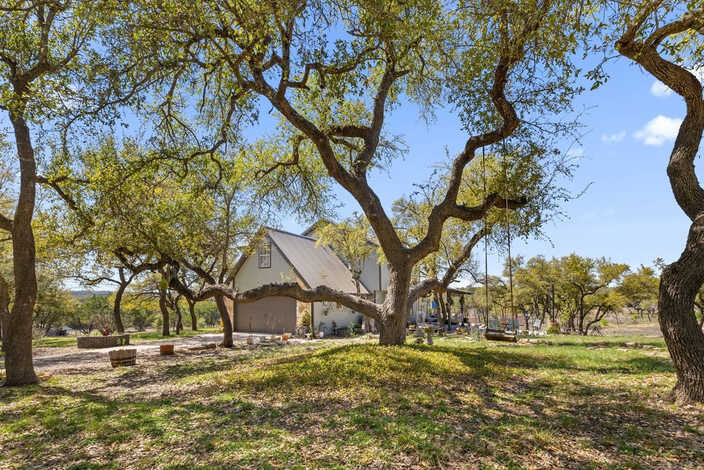 290 Sunset Ridge Dripping Springs, TX 78620 - Photo 5 of 39 a backyard of a house with outdoor seating and trees