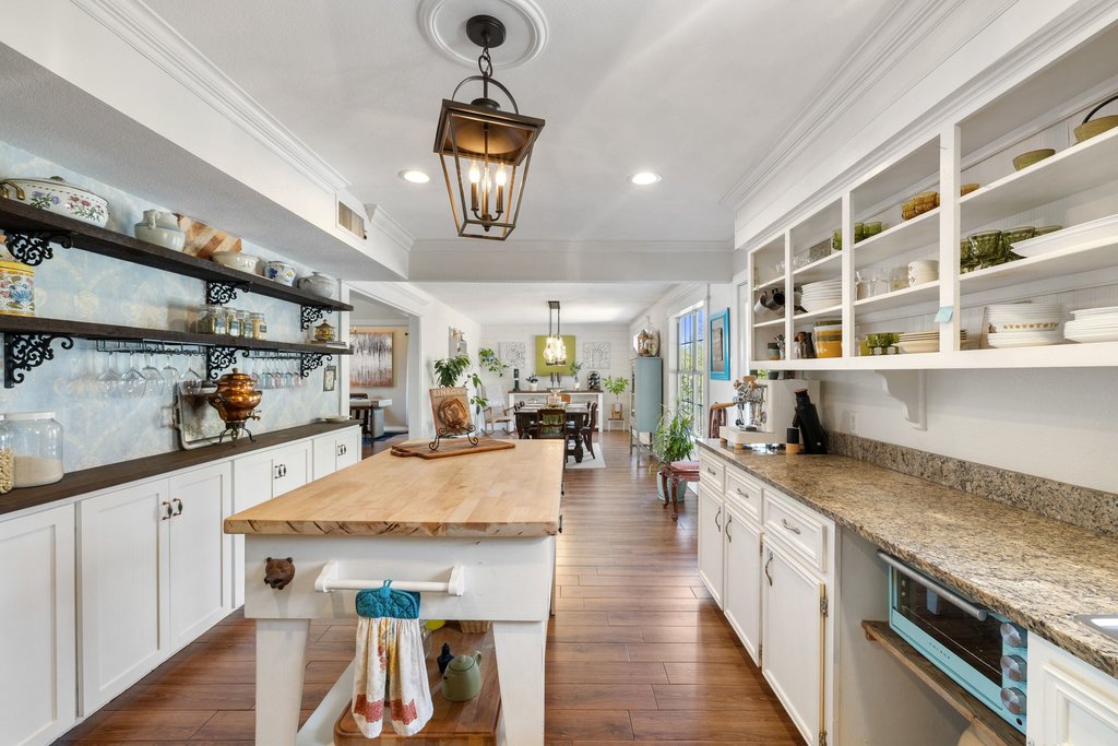 290 Sunset Ridge Dripping Springs, TX 78620 - Photo 8 of 39 Kitchen featuring open shelves, white cabinets, hanging light fixtures, dark wood-type flooring, and ornamental molding