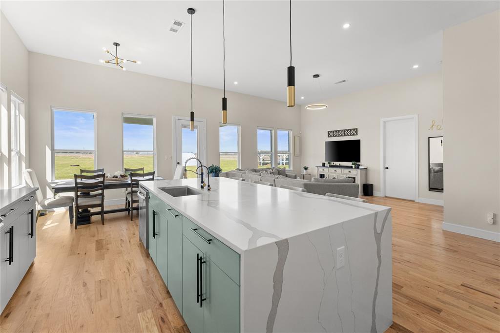 1568 County Road 3517 Quinlan, TX 75474 - Photo 7 of 30 a large kitchen with stainless steel appliances kitchen island granite countertop a large center island a stove a sink a dining table and chairs with wooden floor
