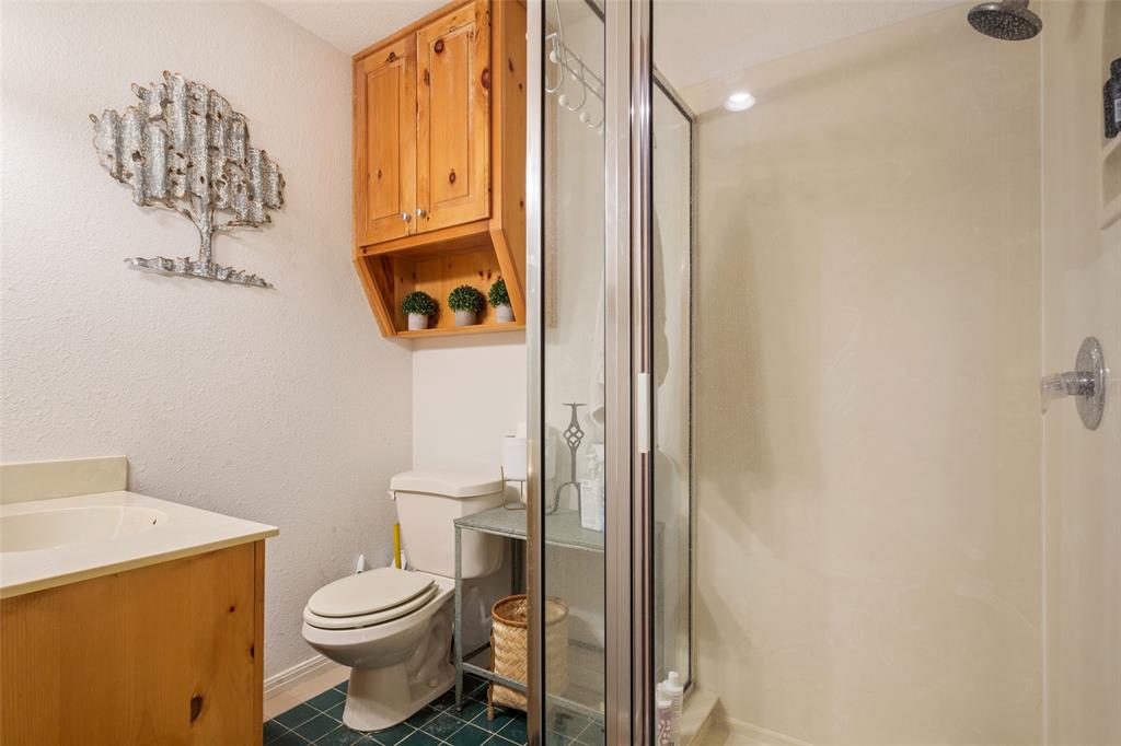 564 Sam Bass Road McGregor, TX 76657 - Photo 22 of 37 Bathroom featuring a glass-enclosed shower, a wood-finish vanity with an integrated sink, and an overhead wood-finish cabinet with open shelving