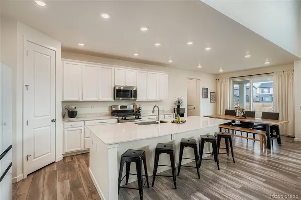 a kitchen with stainless steel appliances a table and chairs in it