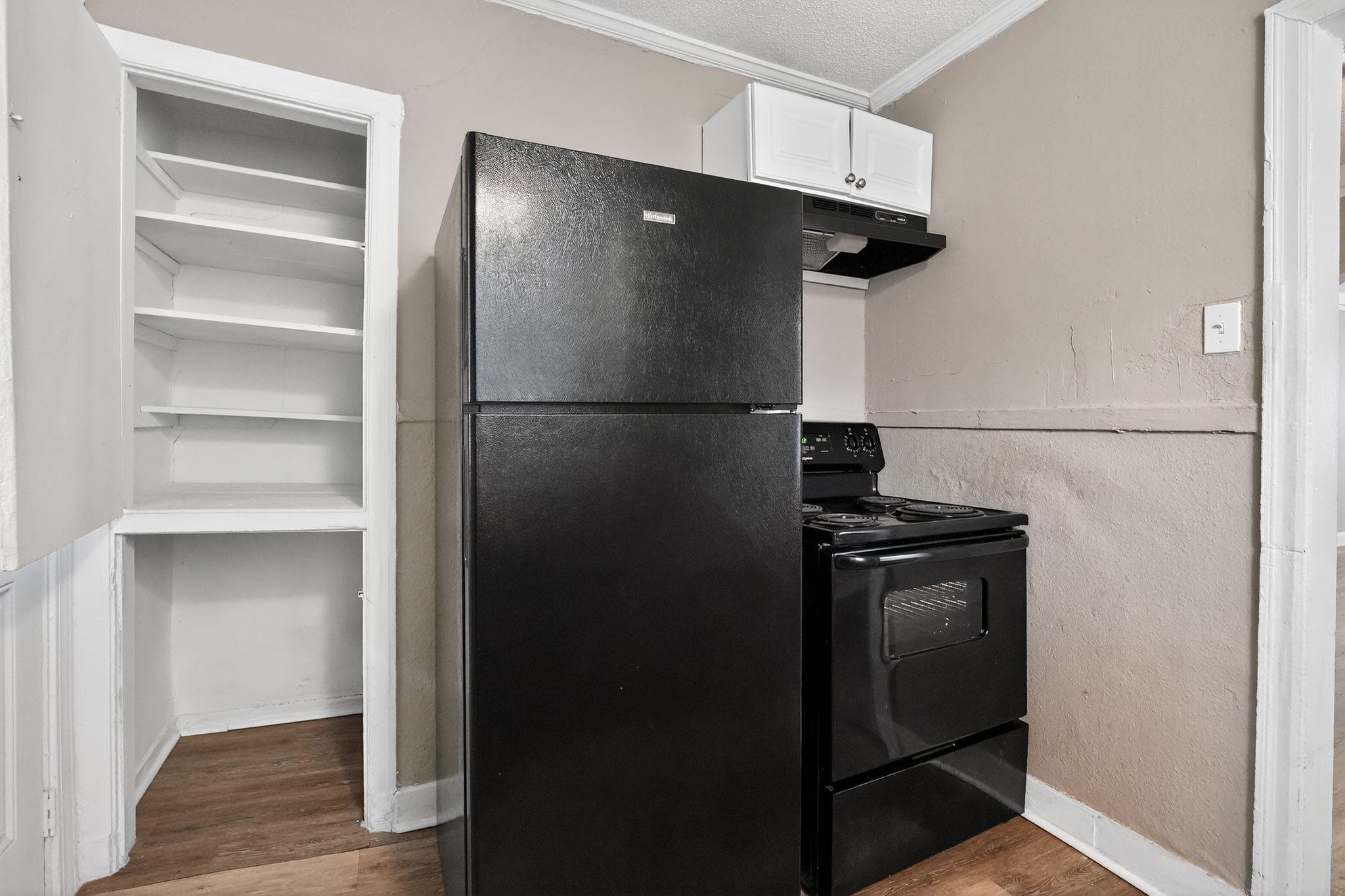 356 Hewlett Road Memphis, TN 38109 - Photo 12 of 30 a view of a refrigerator in kitchen and an empty room with wooden floor