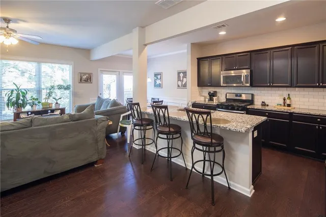 a living room with furniture dining table wooden floor and a large window