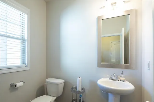 a bathroom with a toilet a sink a mirror and a window