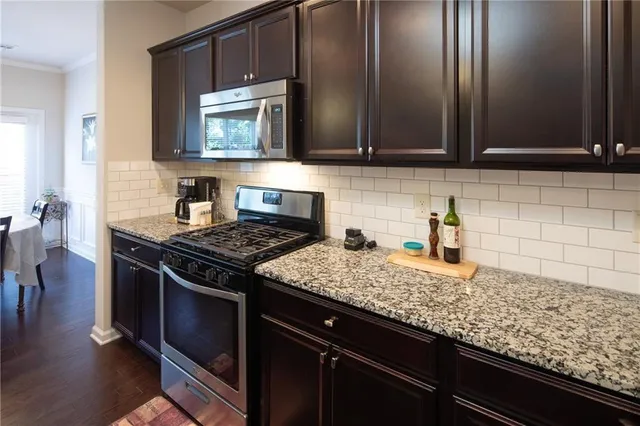 a kitchen with granite countertop a sink a stove and cabinets
