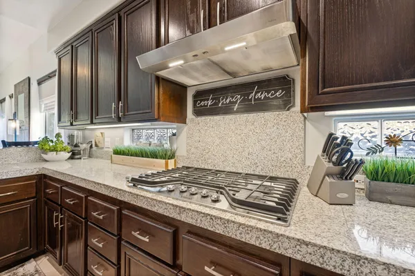 a kitchen with granite countertop wooden cabinets a refrigerator a stove a oven and a sink