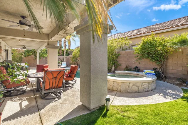a view of a patio with table and chairs potted plants and floor to ceiling window