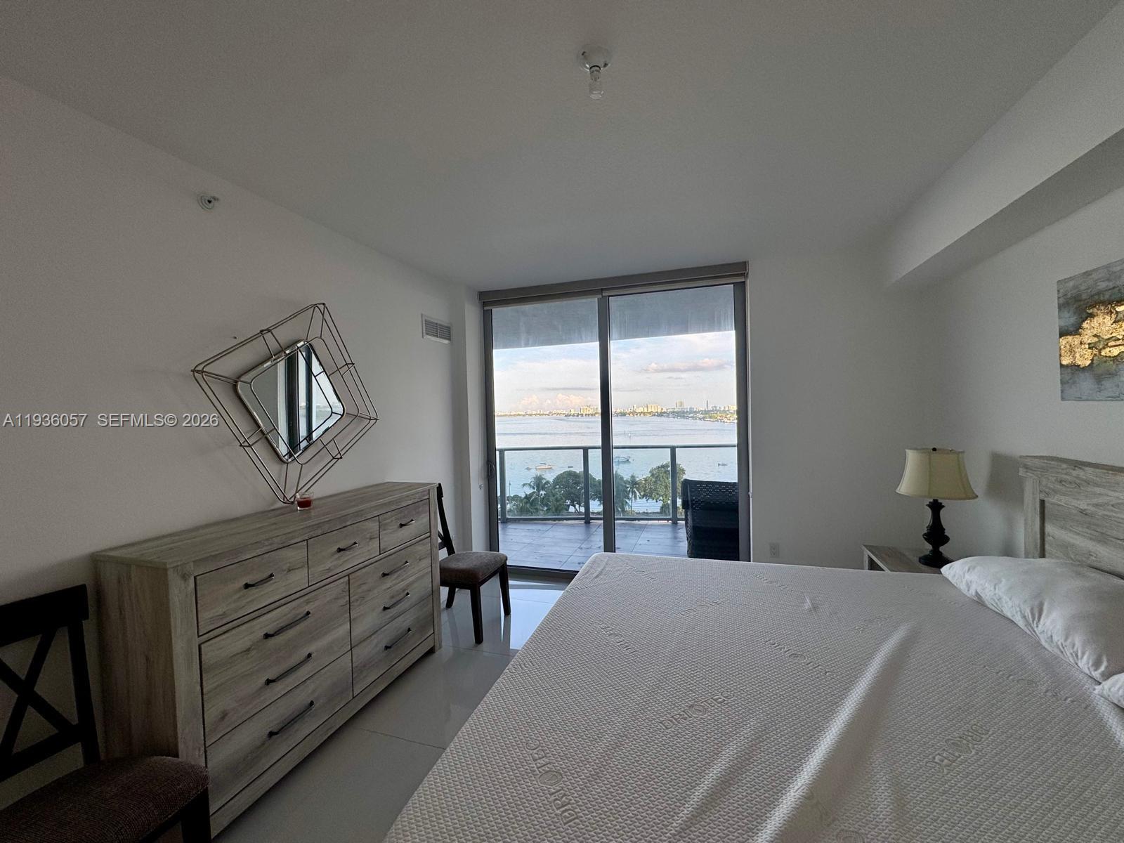 488 Northeast 18th Street, Unit 806 Miami, FL 33132 - Photo 5 of 13 a bedroom with a bed a couch and large window