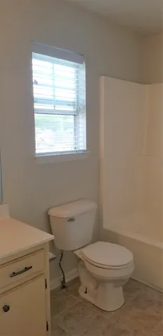 a white toilet sitting next to a window in a bathroom