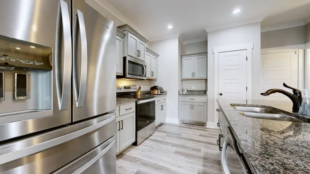 a kitchen with granite countertop white cabinets and stainless steel appliances