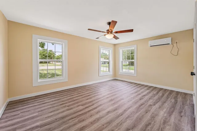 a view of an empty room with a window and wooden floor