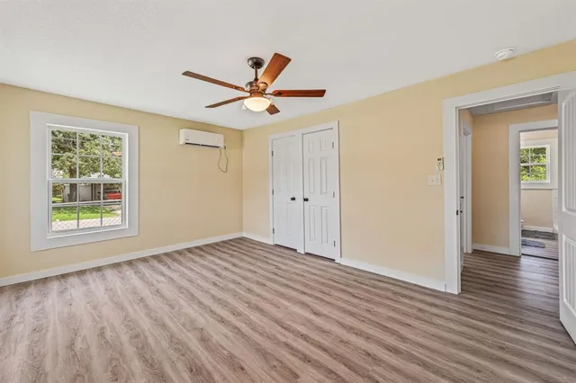 a view of empty room with wooden floor and fan