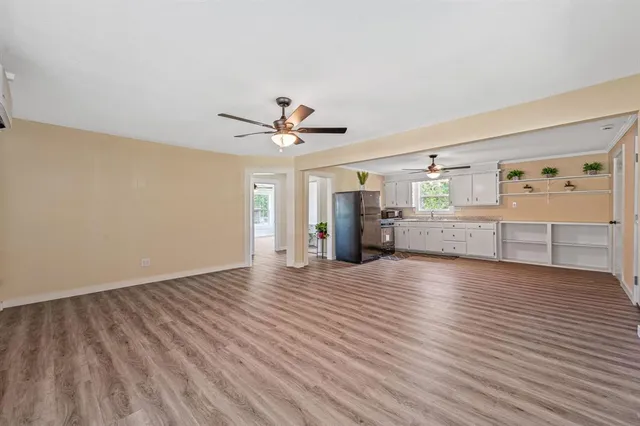 a view of an empty room with a window and wooden floor