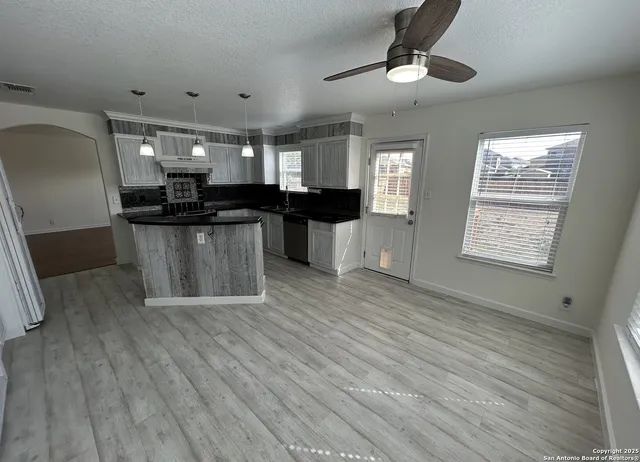 a kitchen with stainless steel appliances wooden floor and chandelier