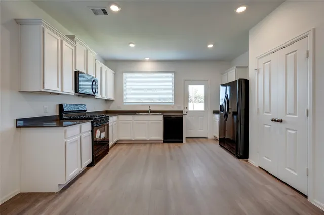 a kitchen with a refrigerator a stove top oven and wooden floor