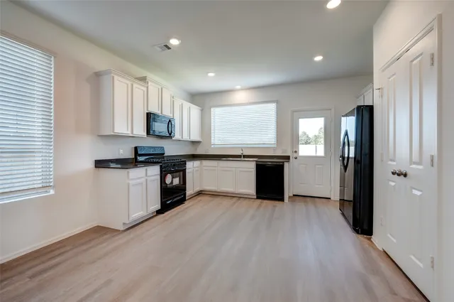 a kitchen with granite countertop a refrigerator stove top oven and sink