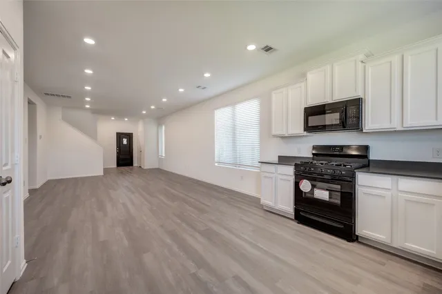 a kitchen with granite countertop a refrigerator and a stove top oven