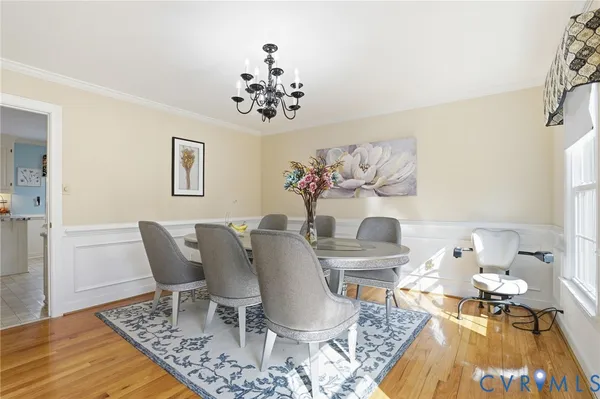 a dining room with wooden floor and a chandelier