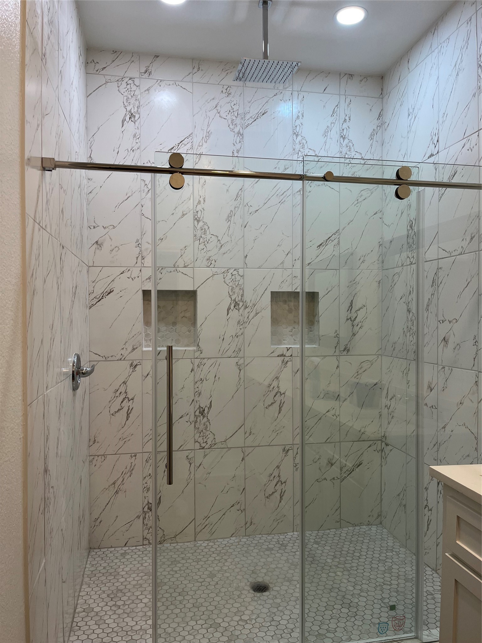33416 FM 521 Road Angleton, TX 77515 - Photo 16 of 21 This photo shows a modern shower with a sleek glass door, Tiled walls, and a rainfall showerhead. It features built-in niches for storage and recessed lighting for a bright, luxurious feel.