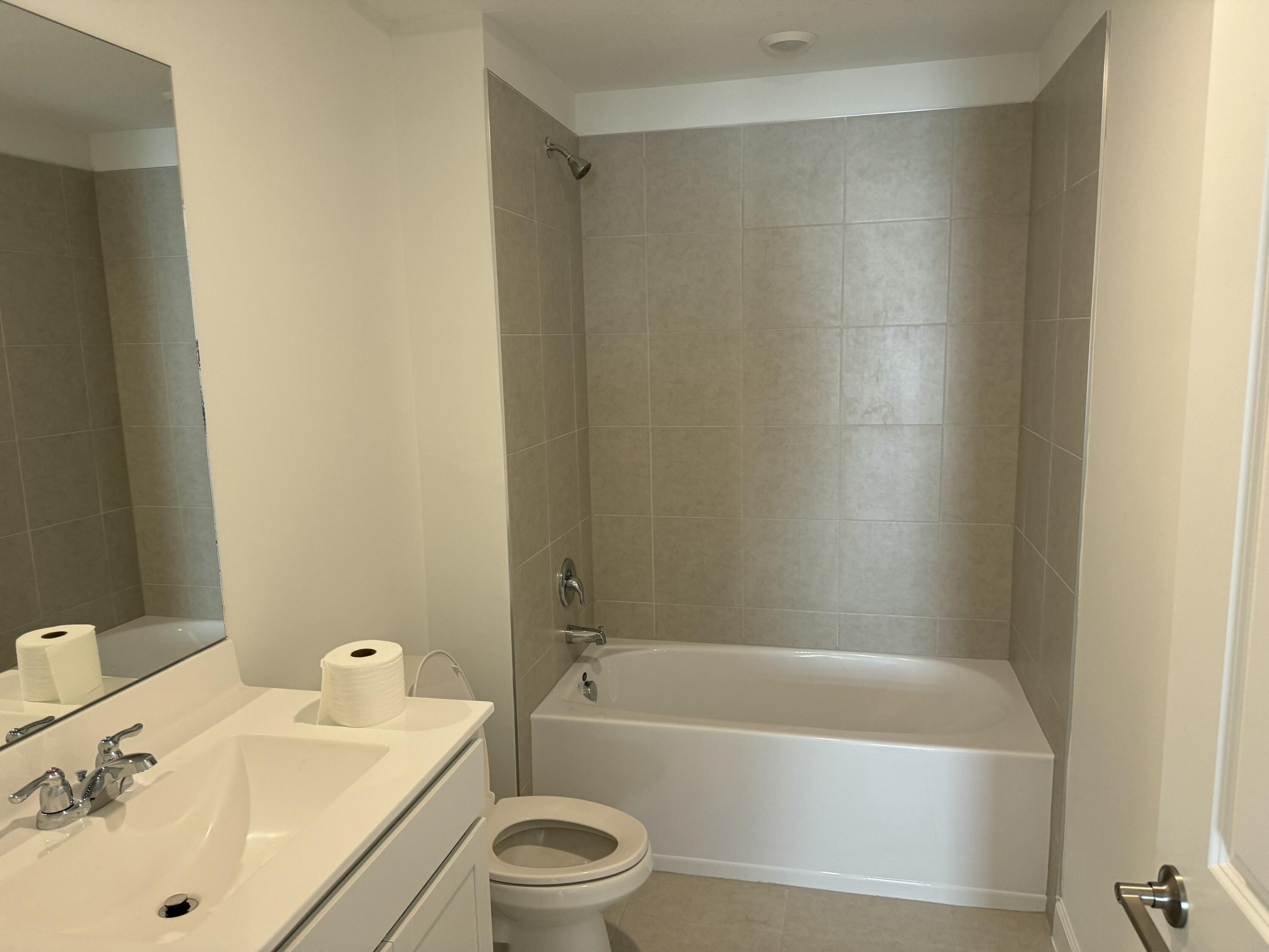 10501 Northwest Suncrest Loop Port St. Lucie, FL 34987 - Photo 21 of 33 a bathroom with a tub shower sink vanity and toilet