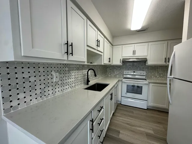 a kitchen with granite countertop a white cabinets and white appliances