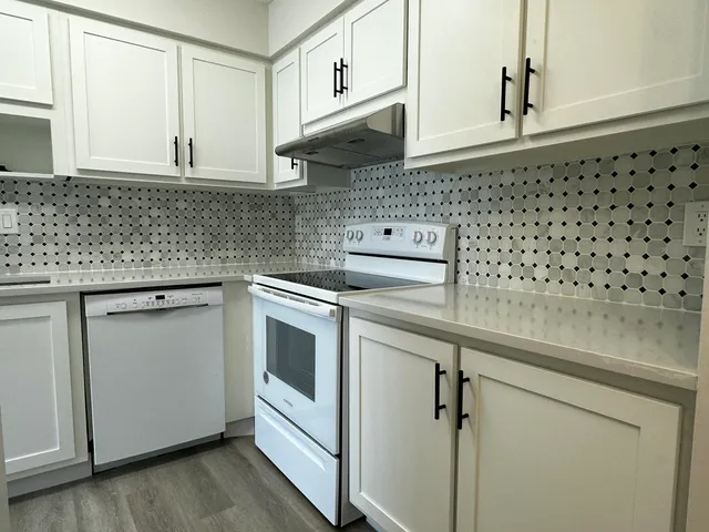 a kitchen with granite countertop white cabinets and white appliances