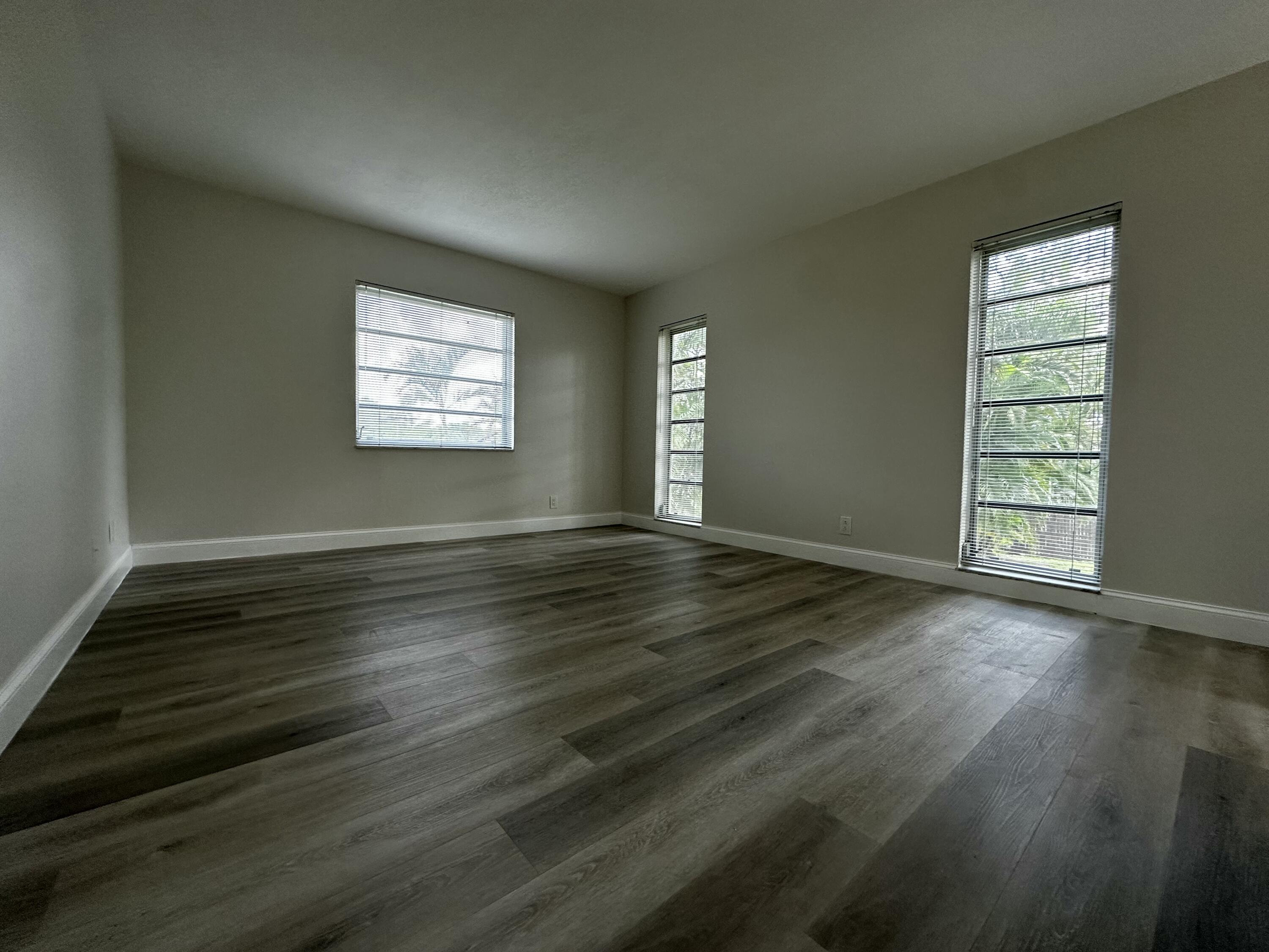 13682 Vía Flora, Unit H Delray Beach, FL 33484 - Photo 17 of 28 an empty room with wooden floor and windows