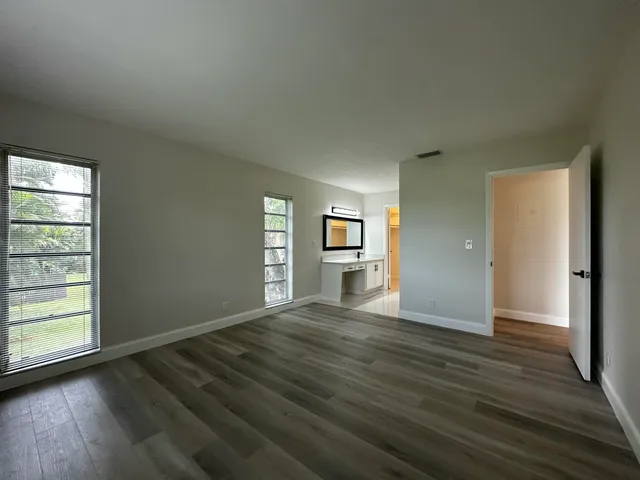 an empty room with wooden floor closet and windows